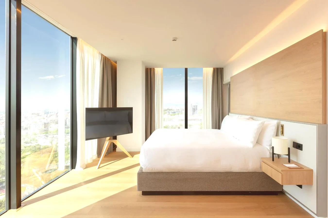Dormitorio con una cama y grandes ventanales con vistas a Barcelona Torre Melina Gran Meliá Hotel