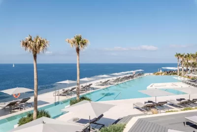Piscina con sombrillas blancas y vista al océano en 7Pines Resort Ibiza, parte de Destination by Hyatt, en San José